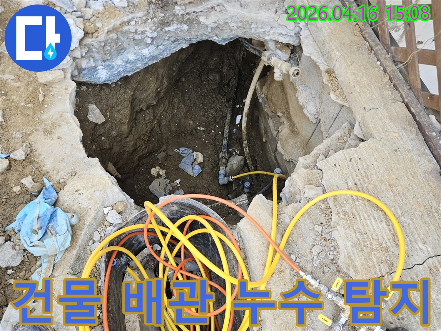 건물 내부 배관에서 발생한 누수 지점을 찾아내기 위해-땅을 파내고 전문 압력 테스트 장비를 설치하여-정밀하게 진단하는 작업 현장입니다.