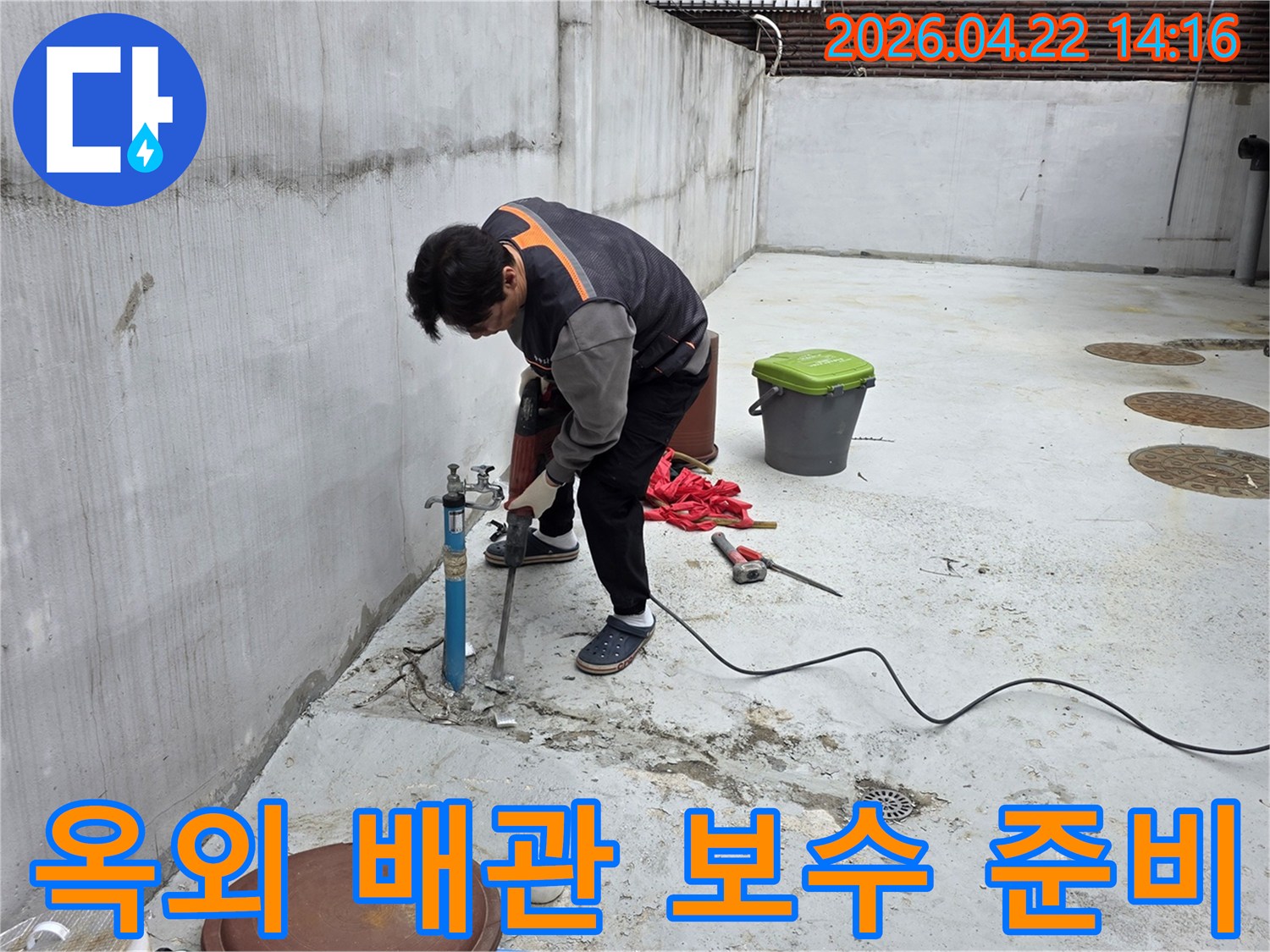 누수 엔지니어가-옥외 배관 누수 보수를 위해-콘크리트를 파쇄하고 현장을 정리하는 모습