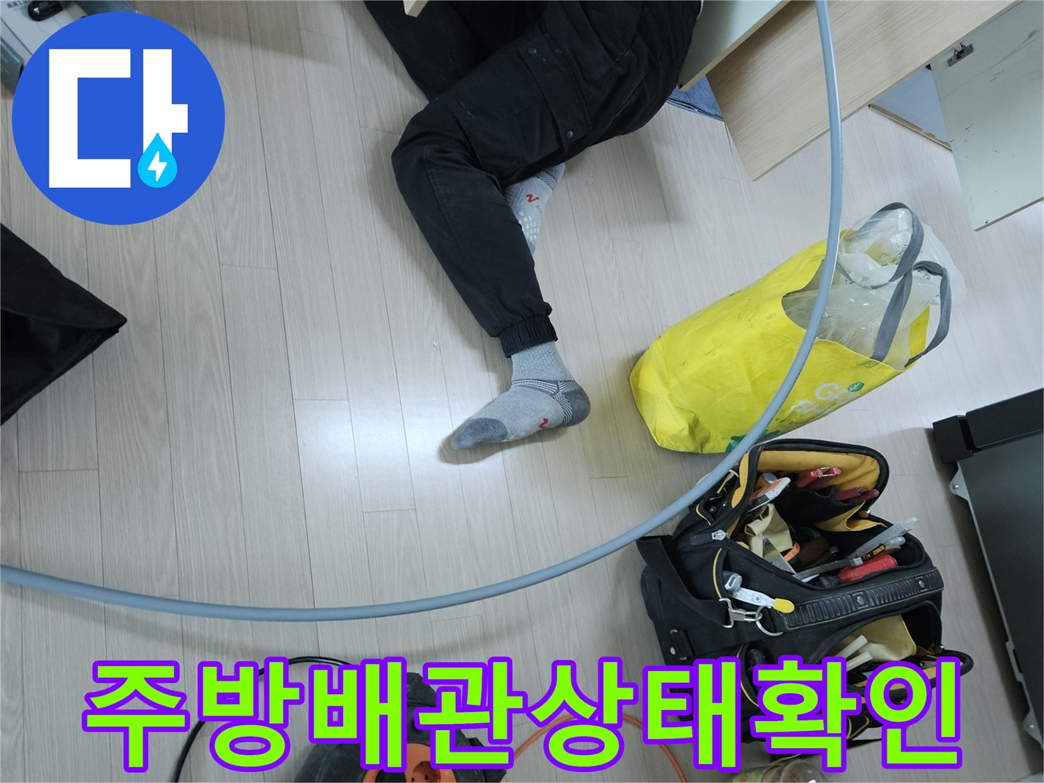 작업자가 싱크대 하단 공간에서 배관을 점검하고 있습니다.