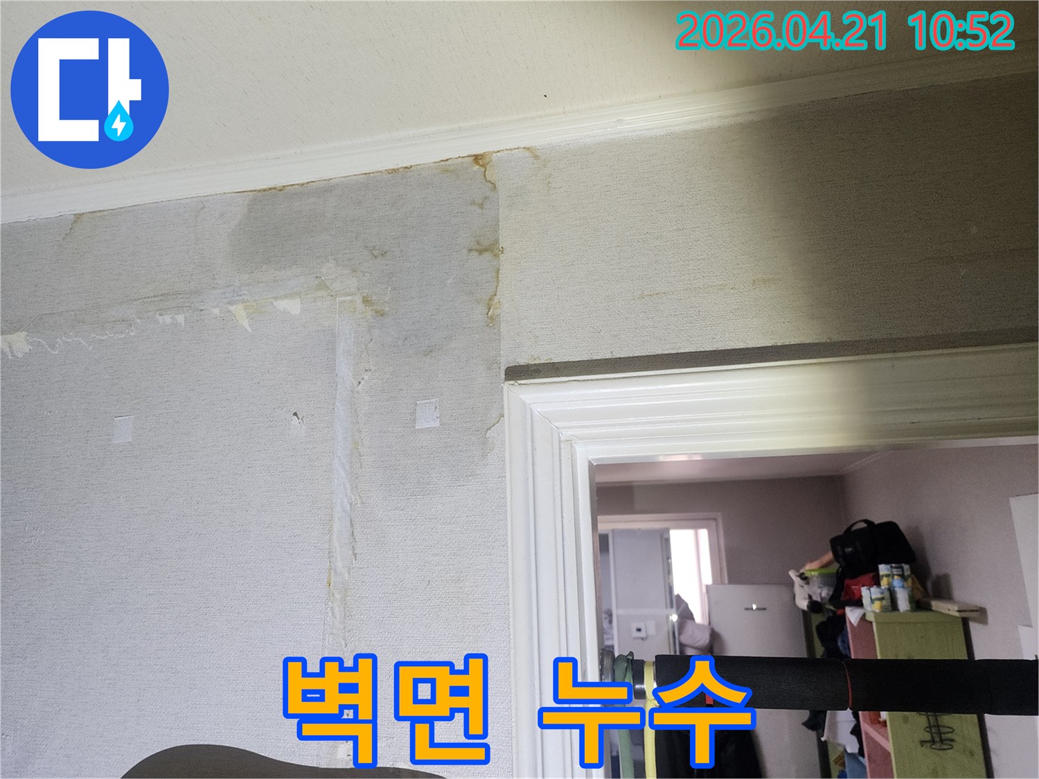 천장과 벽면의 경계 부위에서 물이 새어 벽지가 젖고 변색된-누수 피해 상황을 상세히 보여줍니다.