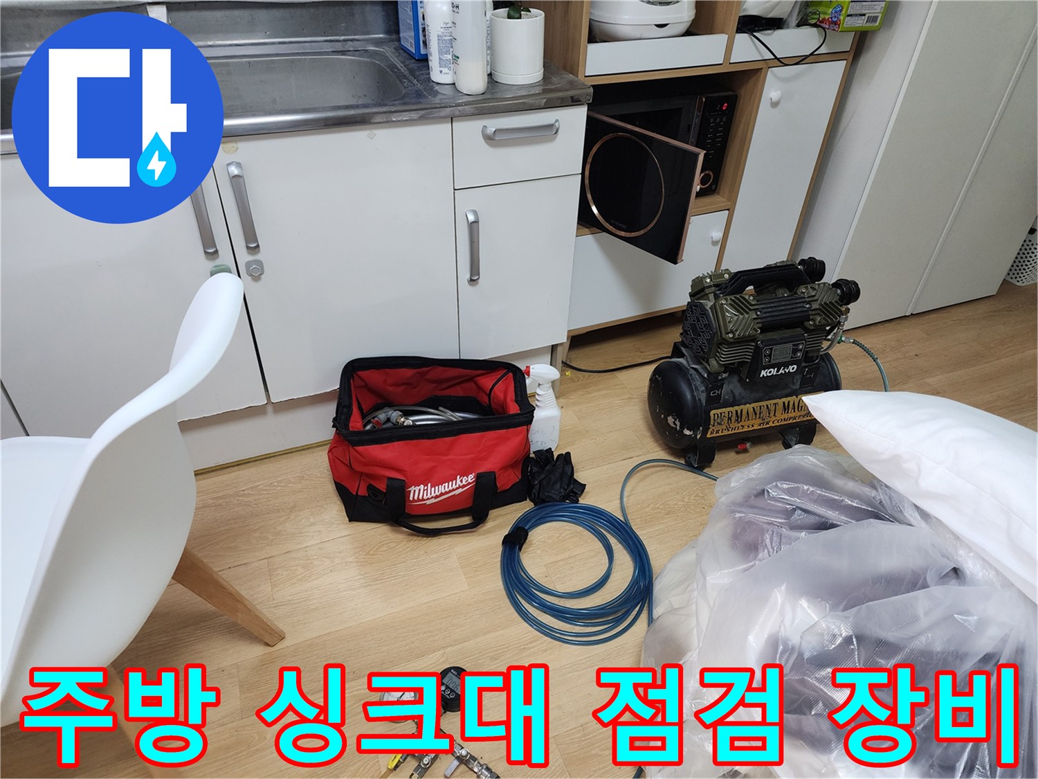 주방 싱크대 하부장 주변에 배치된 누수 탐지용 전문 장비와 공구 가방