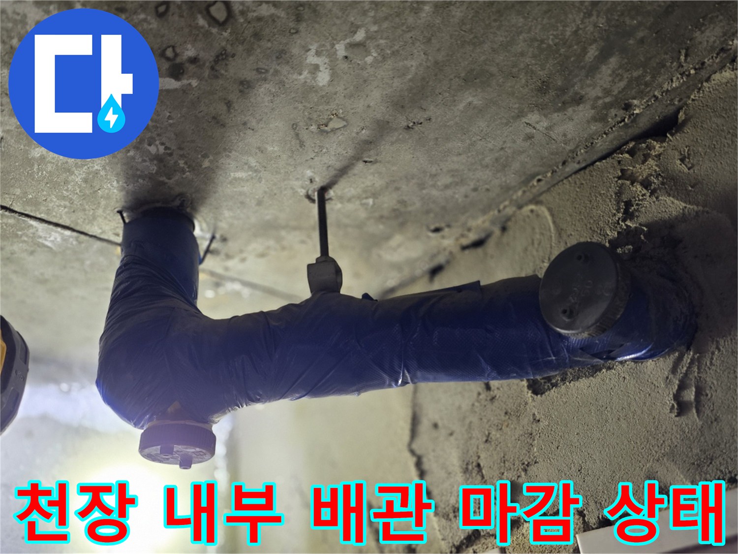어두운 천장 공간 속 파란색 보온재가 씌워진 배관의 모습