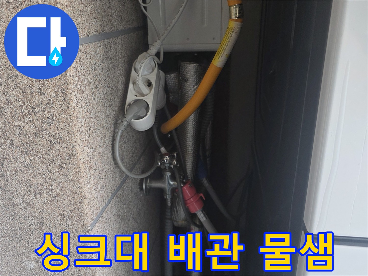 노란색 배수 호스와 은색 부품이 연결된 싱크대 내부 모습