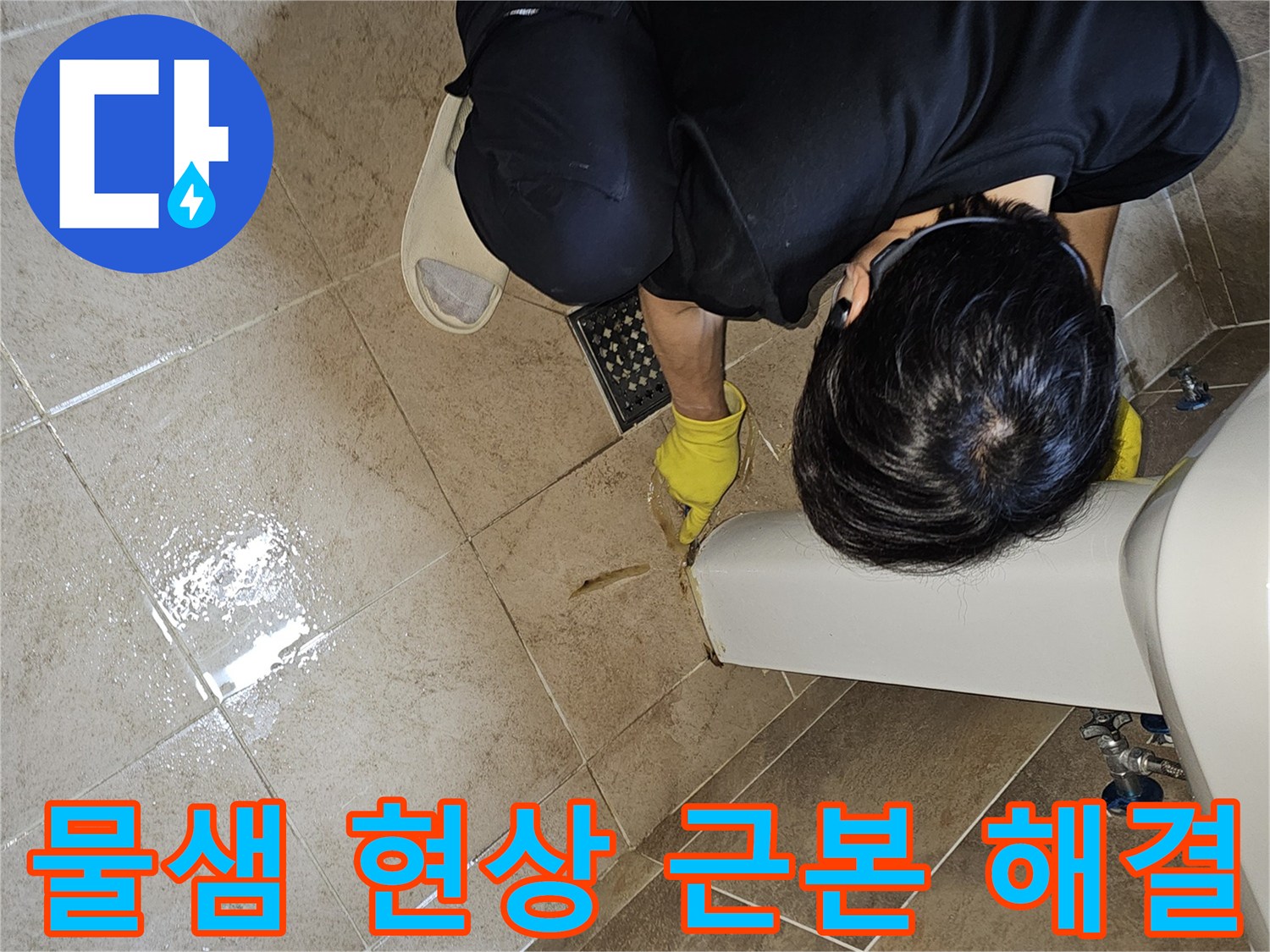 전문 엔지니어가-노란 장갑을 끼고-욕실 바닥의 젖은 타일과-세면대 하단부를-집중적으로 관찰하며-누수 지점을 근본적으로 해결하기 위해-원인을 파악하고 있습니다