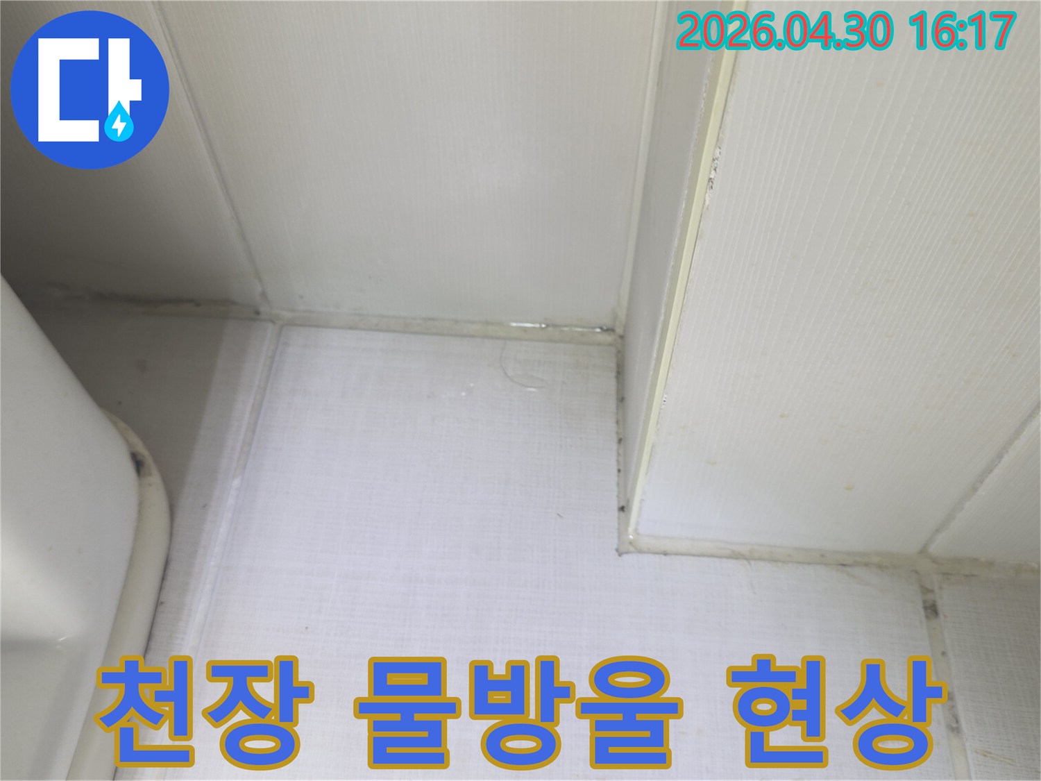 천장과 벽의 접합부에서 물방울이 맺히고-벽지가 젖어있는 상태를 보여주는-누수 발생 현장의 클로즈업 이미지