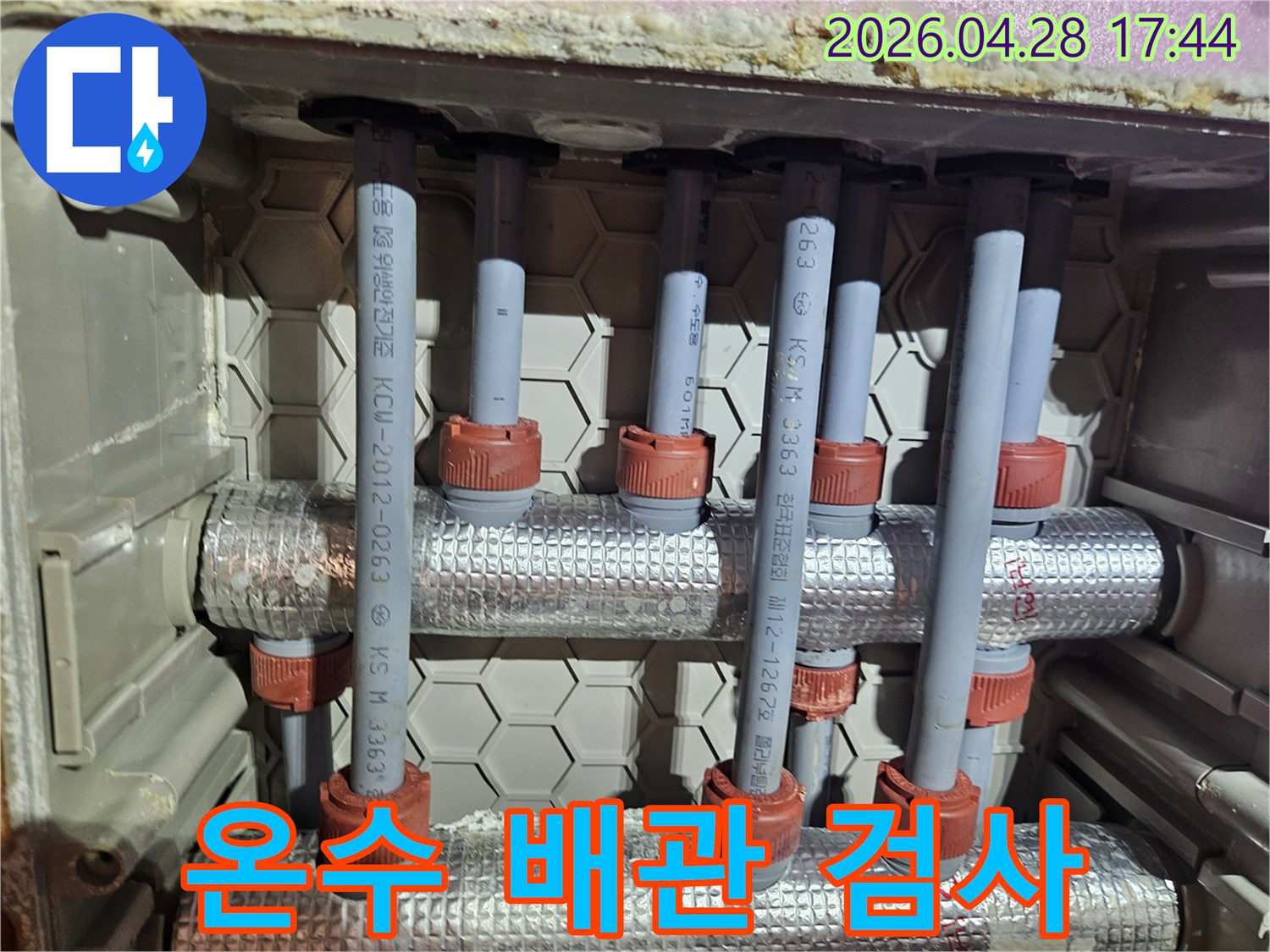 온수 배관의 연결 부위를 검사하는 모습-여러 개의 파이프와 단열재가 얽혀있는 구조
