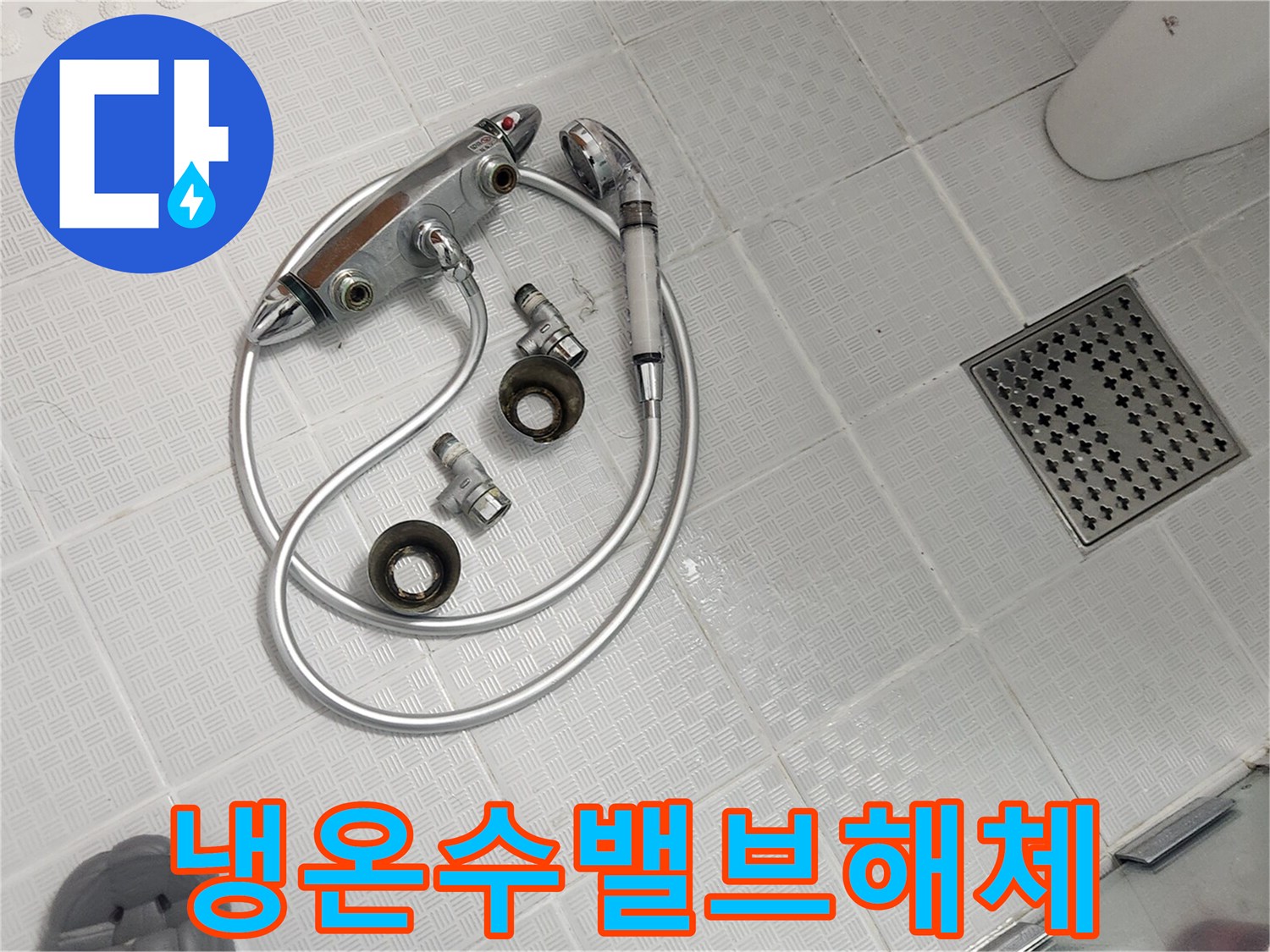 욕실 바닥에 놓인 오래된 샤워기 밸브와 호스-냉온수 조절 불량 해결을 위해 분리된 모습