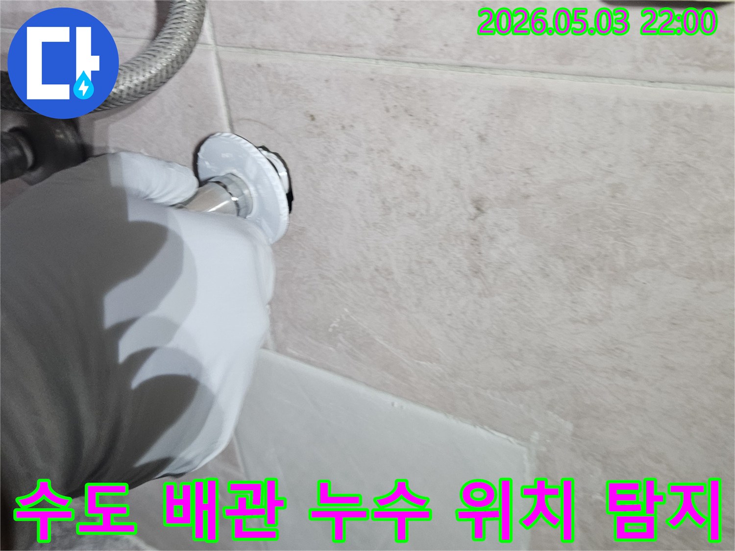 전문 엔지니어가 흰 장갑을 끼고-타일 벽면의 수도 배관 연결 부위를-정밀하게 탐지하여-누수 지점을 찾아내는 작업