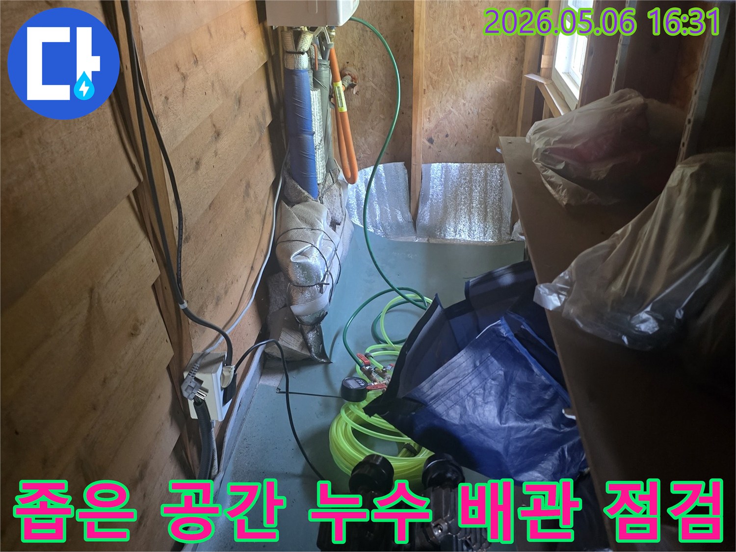 좁은 공간에서-복잡하게 얽힌 배관과 전기선을-꼼꼼히 살피며-누수 지점을 찾는 모습