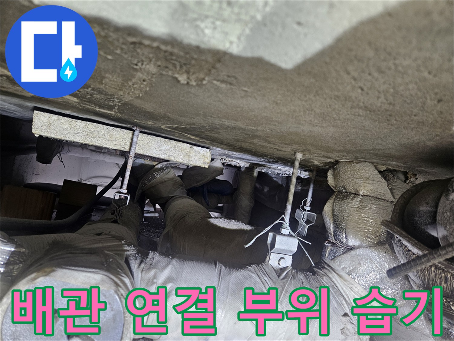 천장 배관의-연결 지점과 단열재에 맺힌 습기를 촬영한 이미지입니다.