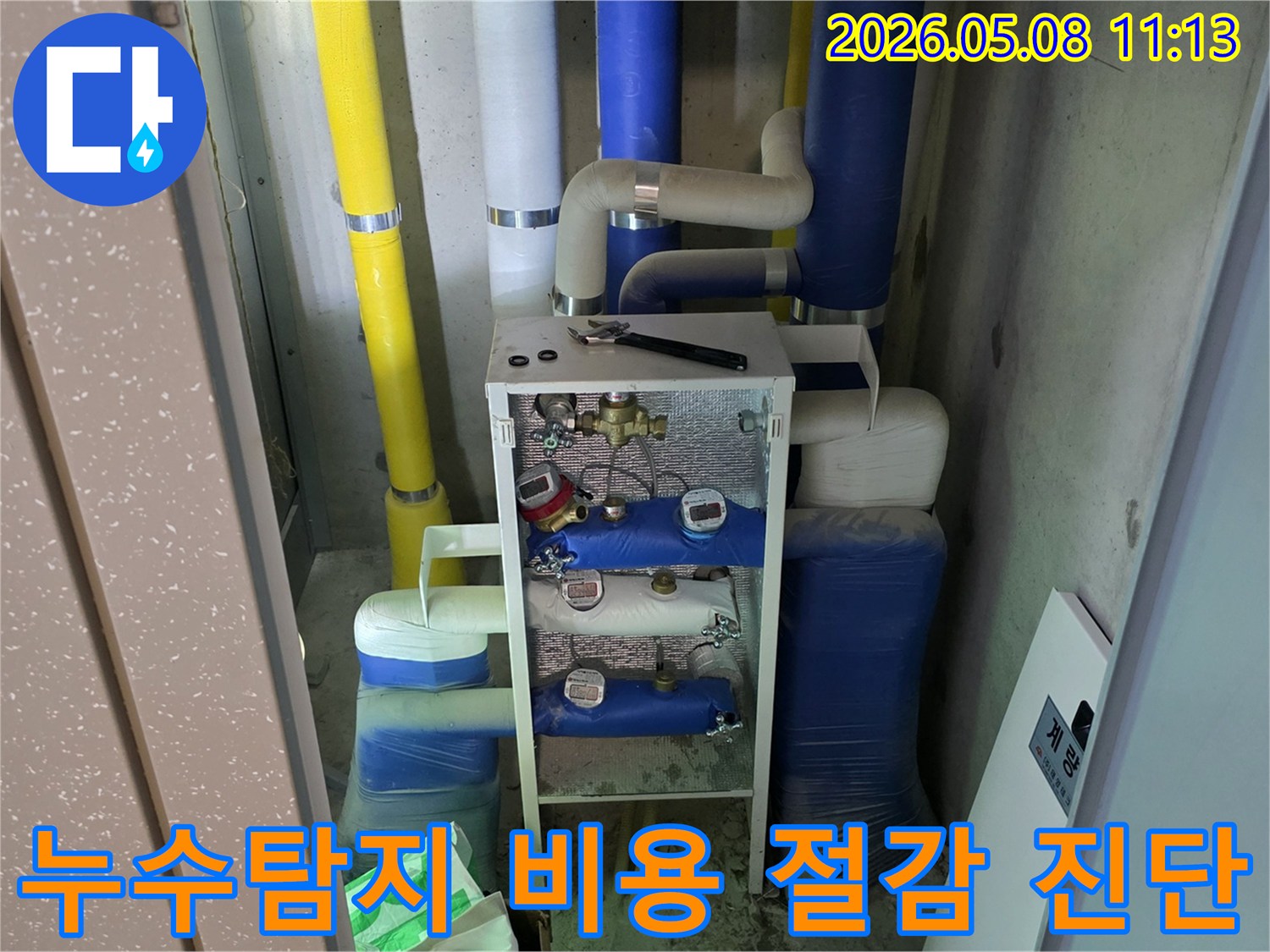 이 이미지는 건물의 유틸리티 공간에 설치된-다양한 배관과 계량기-그리고 작업 도구를 보여주며-이는 누수탐지 비용을 절감하기 위한-정밀 진단 과정을 나타냅니다