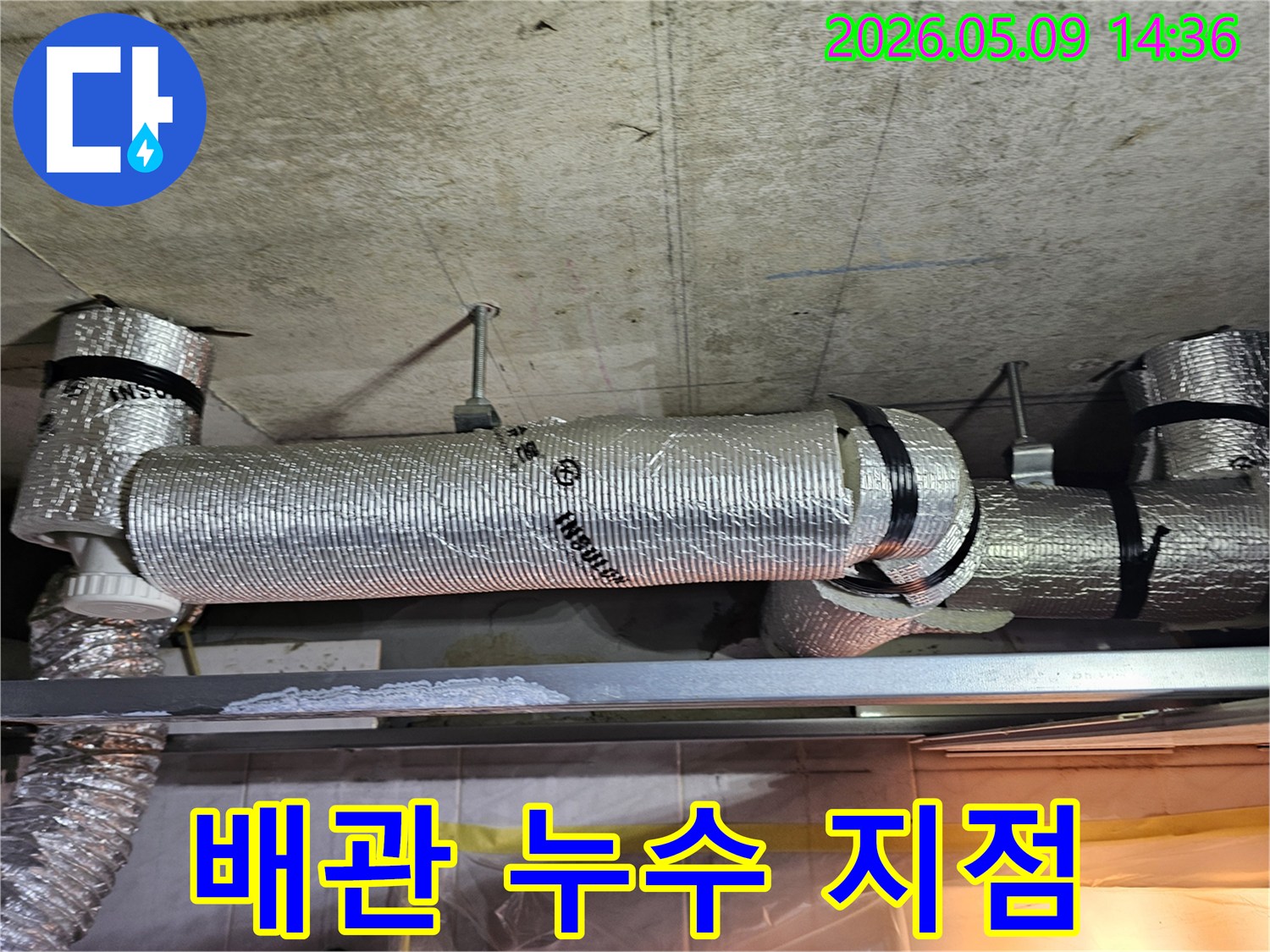 천장 콘크리트 구조물에 고정된 단열 배관 아래 금속 선반에 하얗게 굳은 물 자국