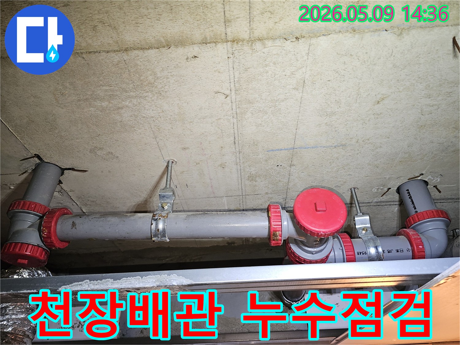 콘크리트 천장에 설치된 회색 배관과 붉은색 연결 부속-누수 점검을 위한 배관 상태 확인