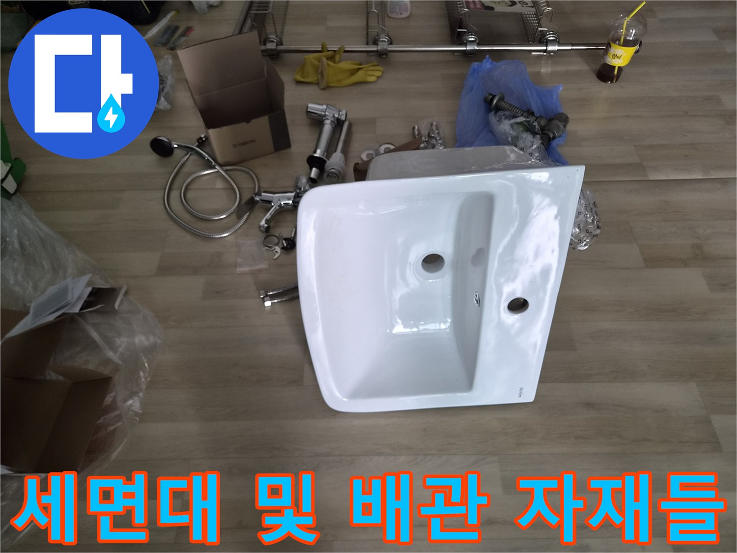 교체용으로 준비된 하얀색 세면대와 은색 배관 부속품