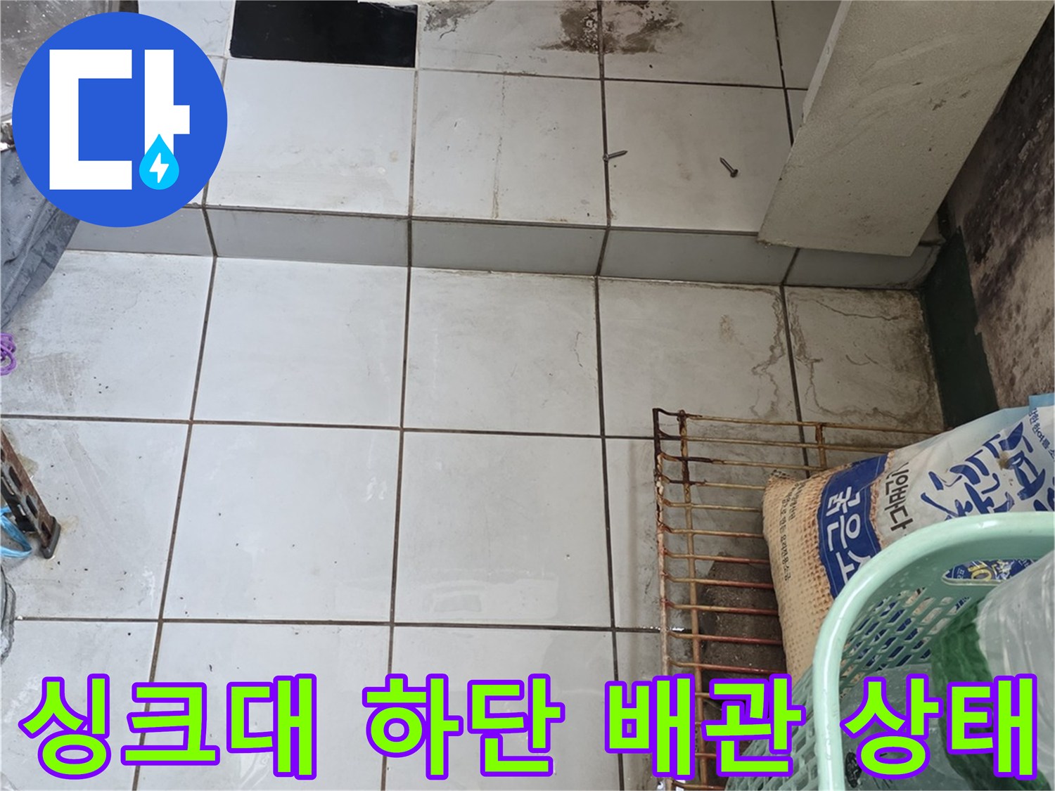 싱크대 밑 벽면 타일과 파란색 보호재가 씌워진 배관 이미지