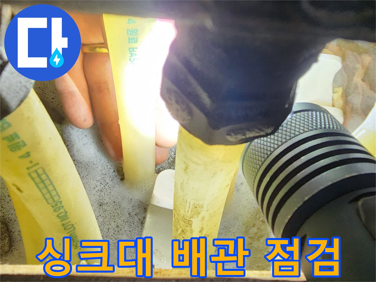 손전등으로 비춘 싱크대 하부장 배관 연결 부위 상태 확인