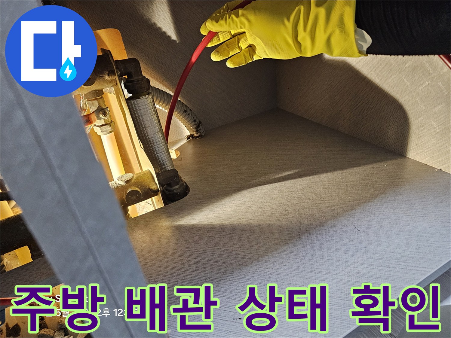 작업자가 장갑을 착용하고 싱크대 아래 배관 연결 부위를 손으로 만져보고 있습니다.