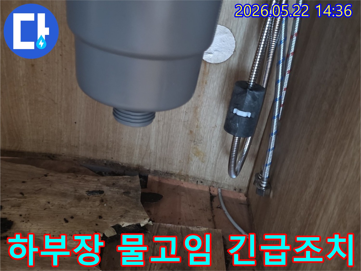 싱크대 하부장 바닥에 고인 물과-물에 젖어 손상된 목재-그리고 배관의 모습을 보여주는 긴급 누수 현장