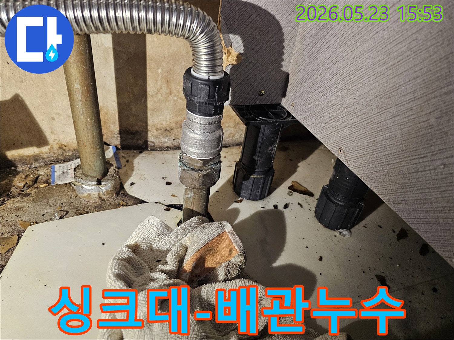싱크대 하부의 배관 연결부에서 물이 새어-바닥에 젖은 수건이 놓인-누수 현장 모습