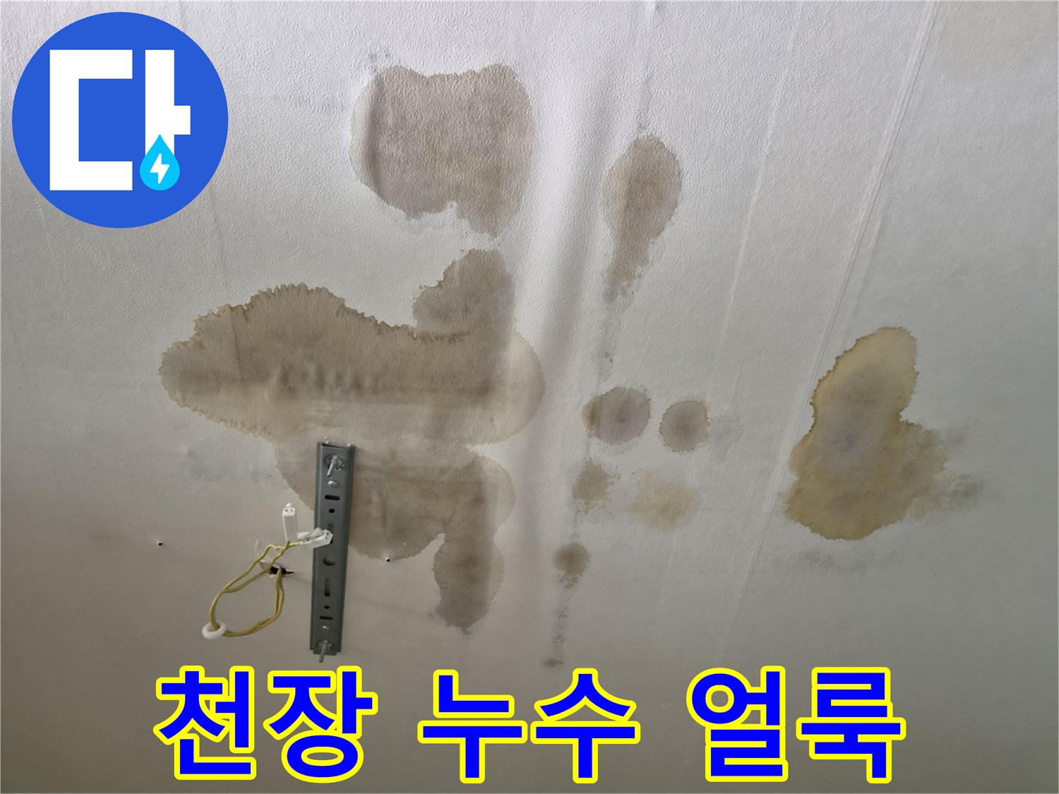 천장 마감재에 발생한 넓은 범위의 습기 얼룩과 전등 배선 노출 상태
