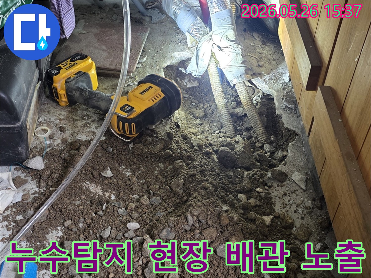 이 이미지는-누수-탐지를-위해-땅을-파서-배관을-노출시킨-현장을-보여줍니다-작업자가-드월트-작업등으로-어두운-곳을-밝히고-있습니다