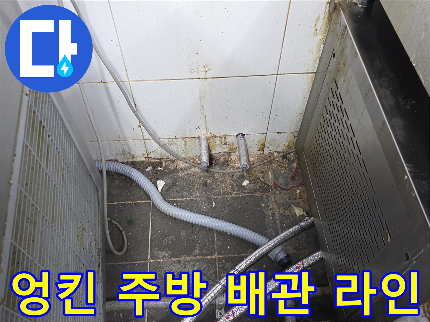 식당 기기 아래 복잡하게 배치된 수도 호스와 배관의 모습입니다.
