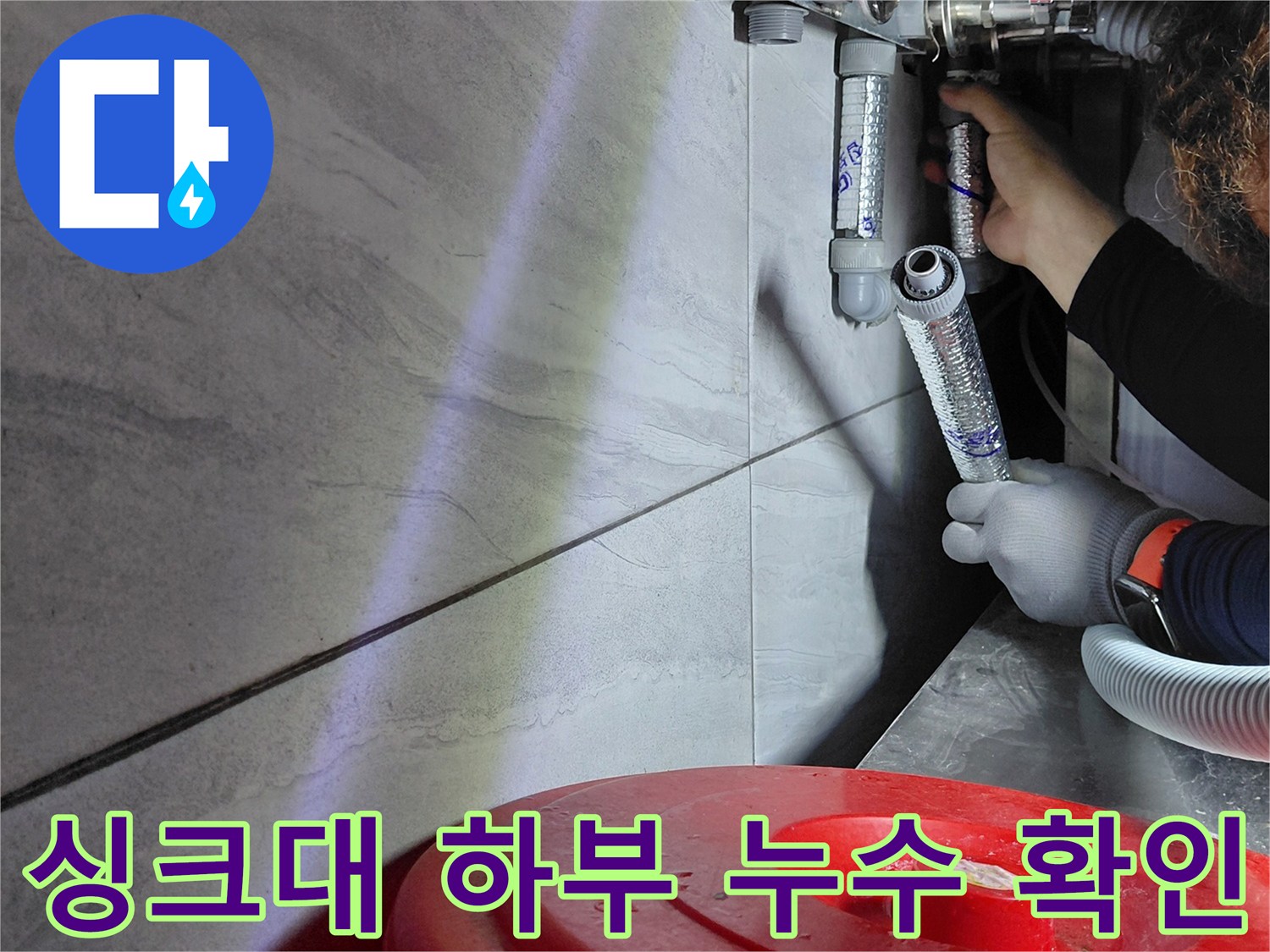 좁은 싱크대 하부 공간에서 배관의 물샘 여부를 점검하는 작업 장면