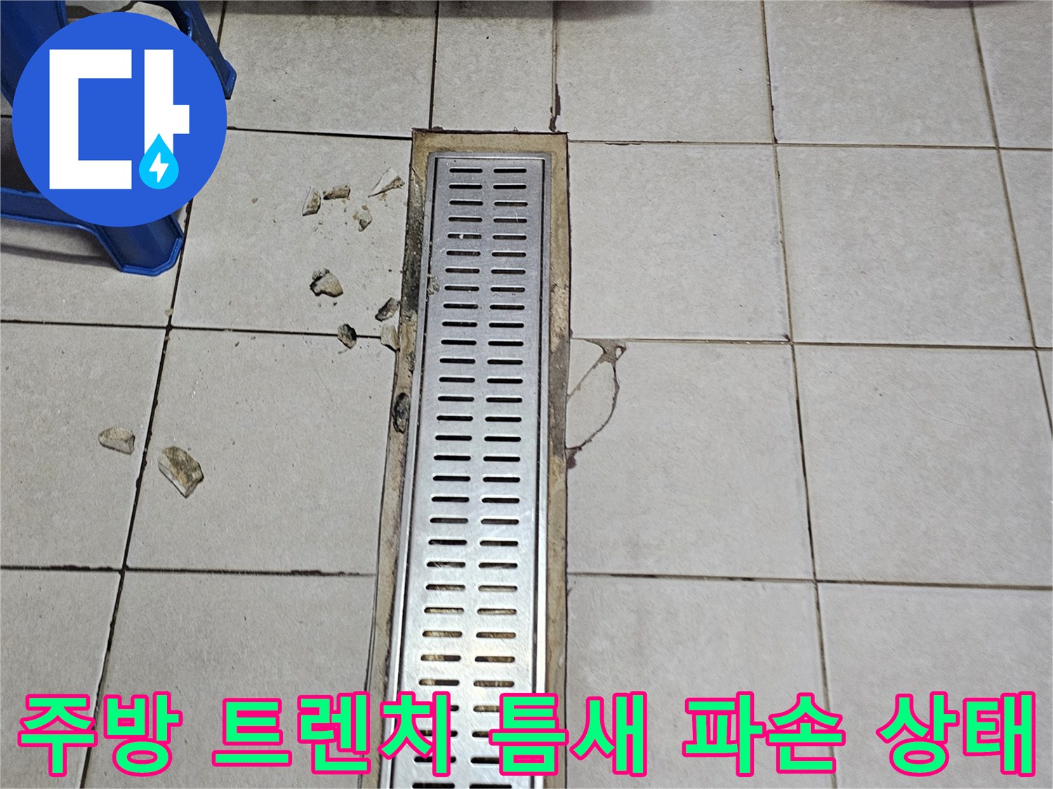 금속 트렌치 덮개 주변의 갈라진 타일과 이물질