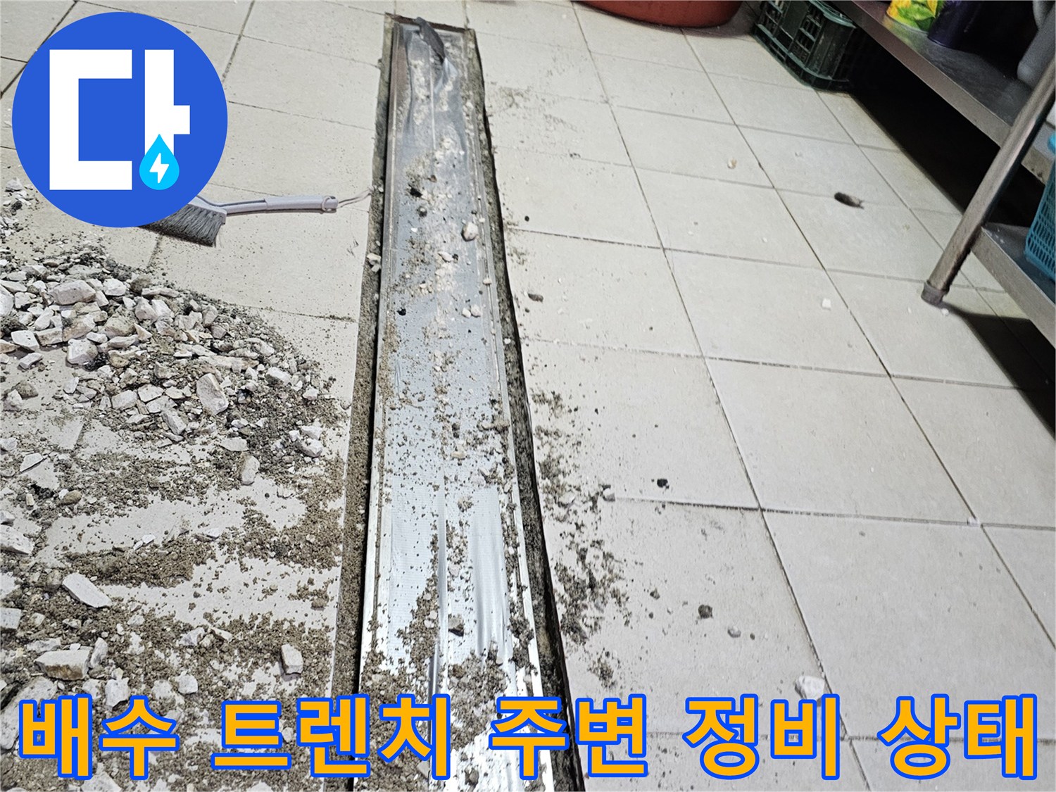금속재질의 긴 배수 트렌치와 깨진 타일 조각들
