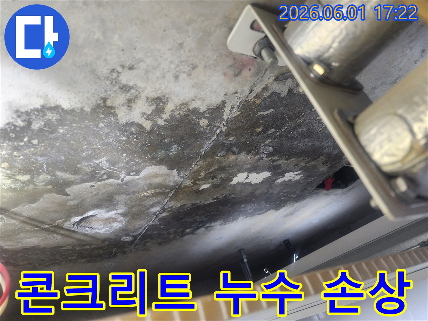 장기간 누수로 인해 심하게 오염되고 부식된 콘크리트 천장-배관 지지대 주변의 물 자국과 균열