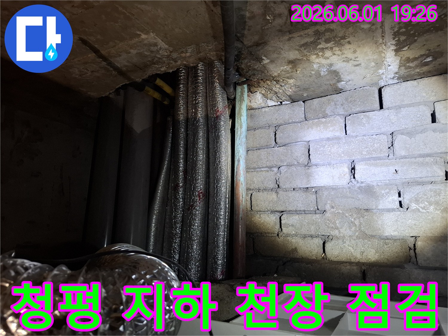 어두운 지하 공간에서-천장 콘크리트와-배관-그리고 젖은 벽돌 벽면의-누수 현장 모습입니다