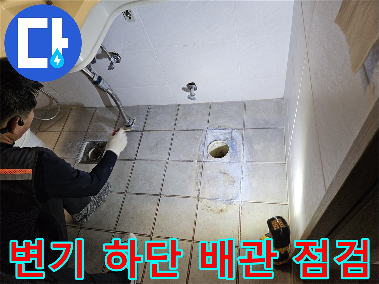 탈거된 변기 자리에 드러난 배관과 타일의 상태를 촬영한 사진입니다.