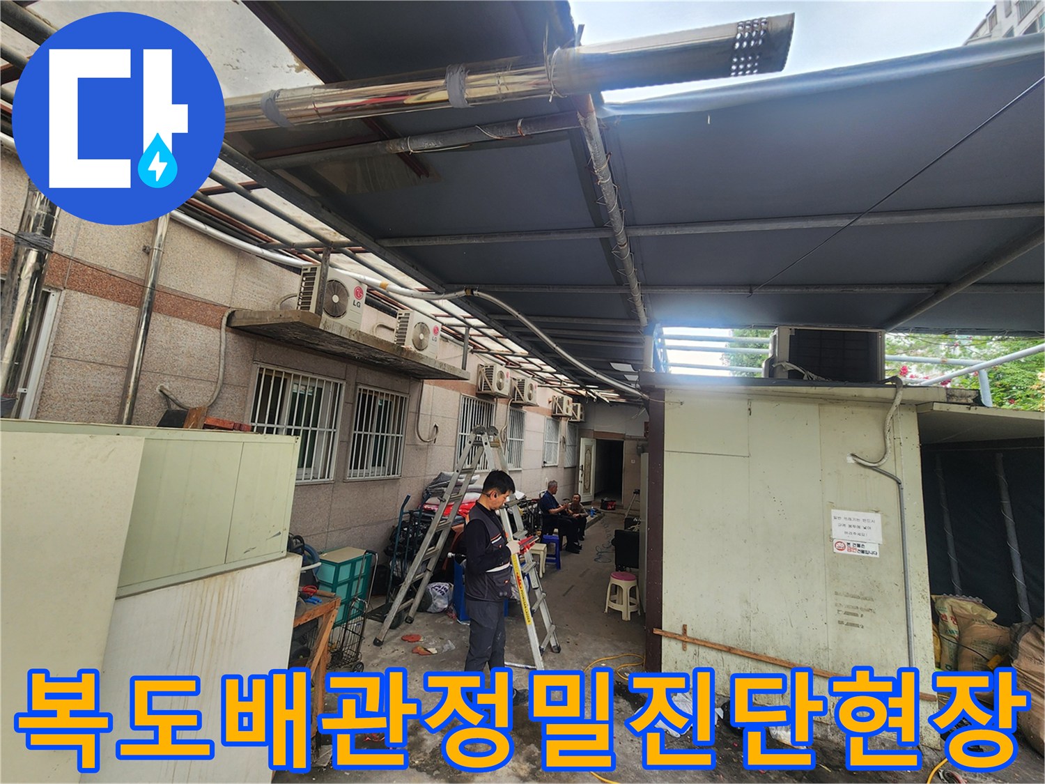 복도 끝쪽 외벽과 인접한 노출 배관 구간을 전문 장비로 정밀하게 진찰하는 장면