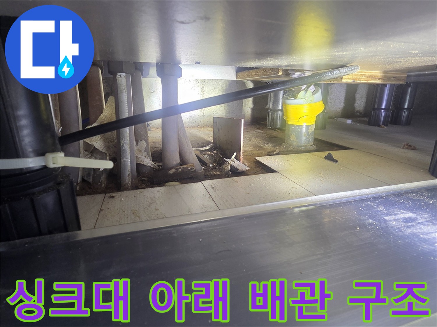 복잡하게 연결된 싱크대 하부의 배관 및 부속품 모습