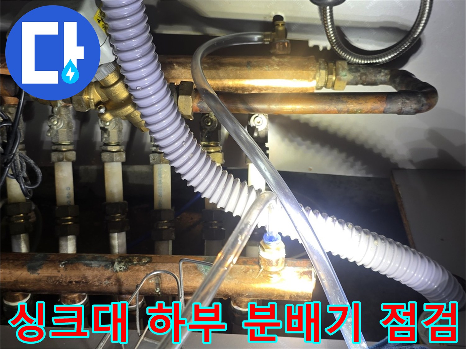 싱크대 아래 보일러 분배기와 연결된 금속 및 고무 배관