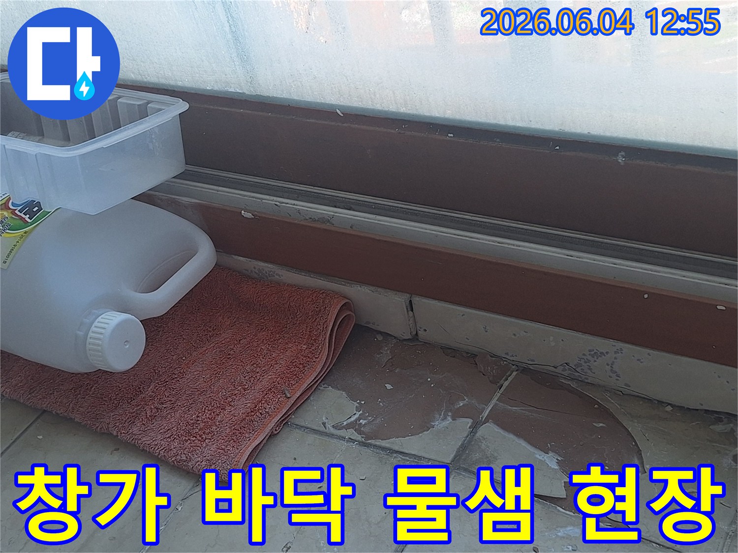 창문 바로 아래 바닥의 물샘 현상-타일 손상과 물기로 인한 변색-누수 지점 파악을 위한 현장 점검-신속한 조치가 필요한 누수 상황