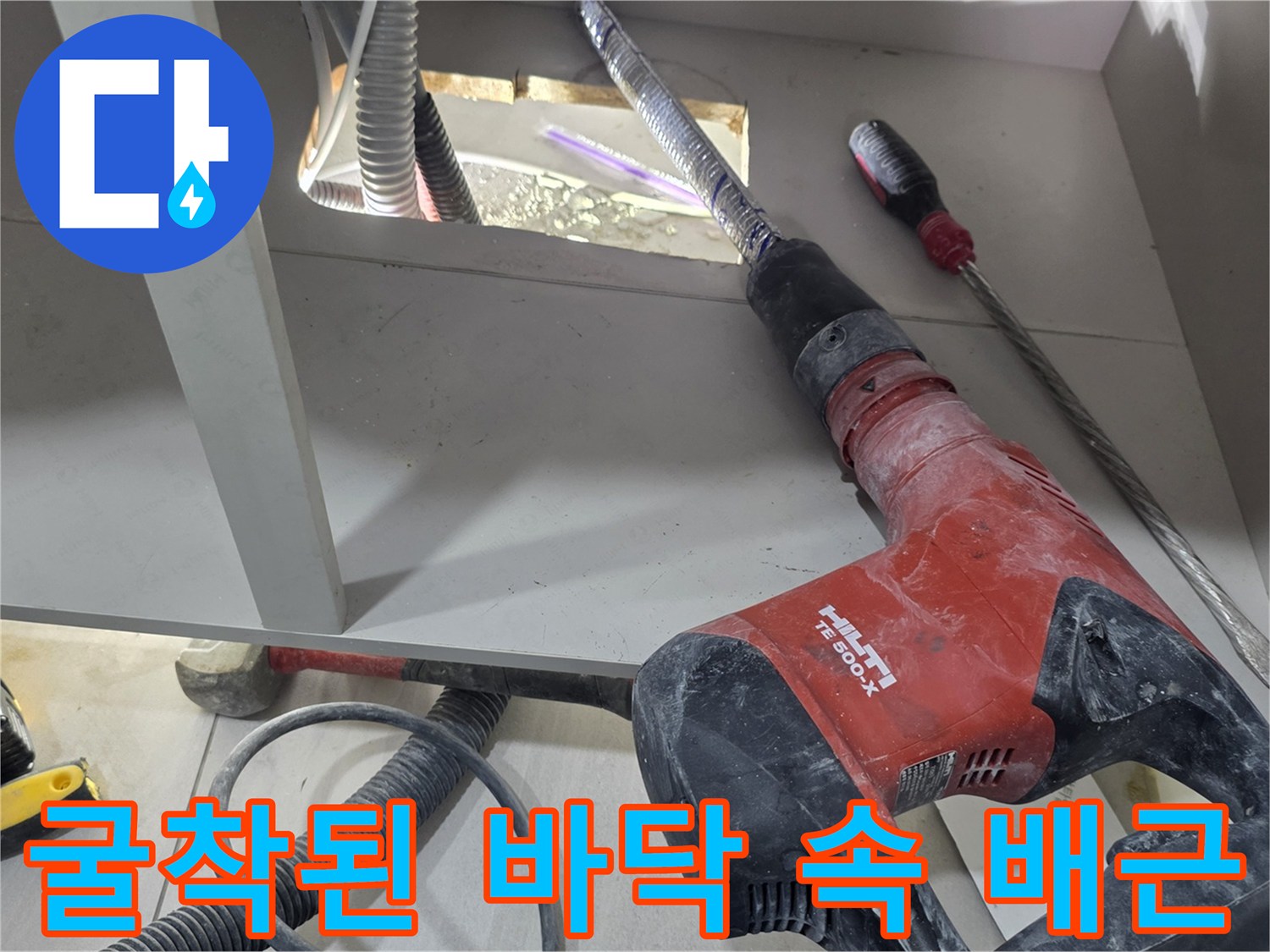 싱크대 밑 굴착 부위에 드러난 배관과 작업 도구의 모습입니다.