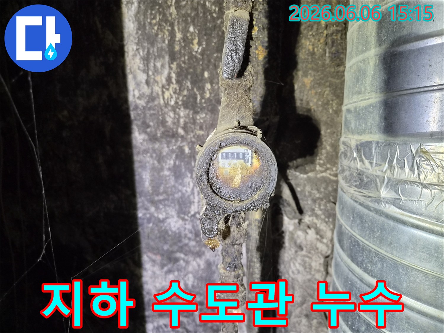 어두운 지하 공간에서 발견된-오래된 수도 계량기와 부식된 배관으로-누수 발생의 직접적인 원인을 보여주며-정확한 진단이 필요한 상황입니다
