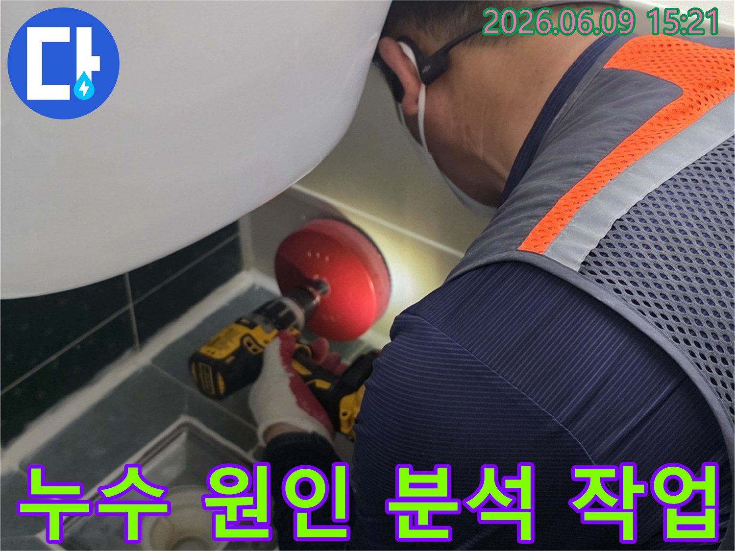 안전-조끼를-입은-전문가가-욕실-배수구-근처의-누수-지점을-정확히-파악하기-위해-전동-공구를-사용하여-작업하는-장면