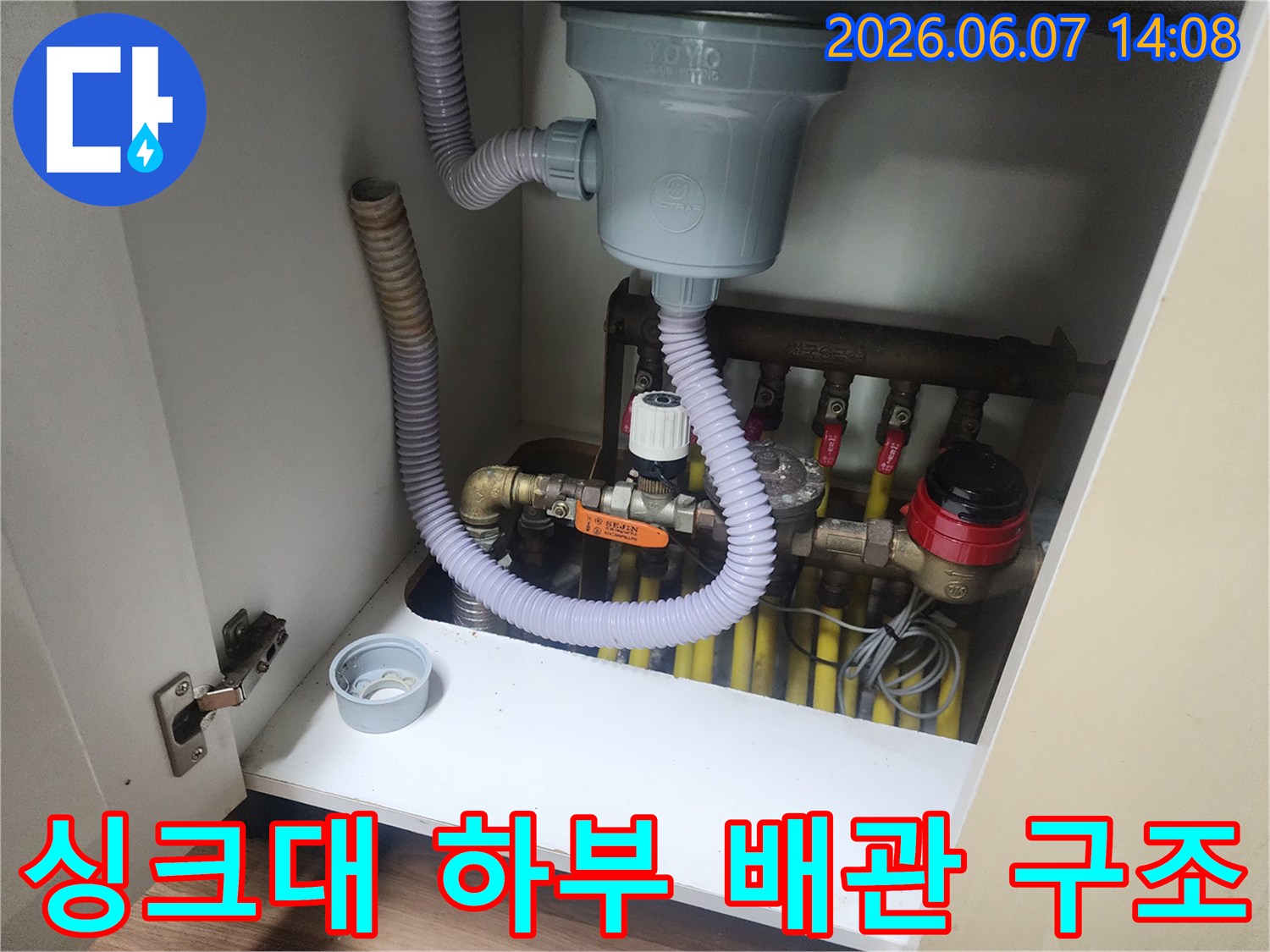 복잡하게 연결된 싱크대 하부의 배수 밸브와 주름관 호스 상세 이미지입니다.