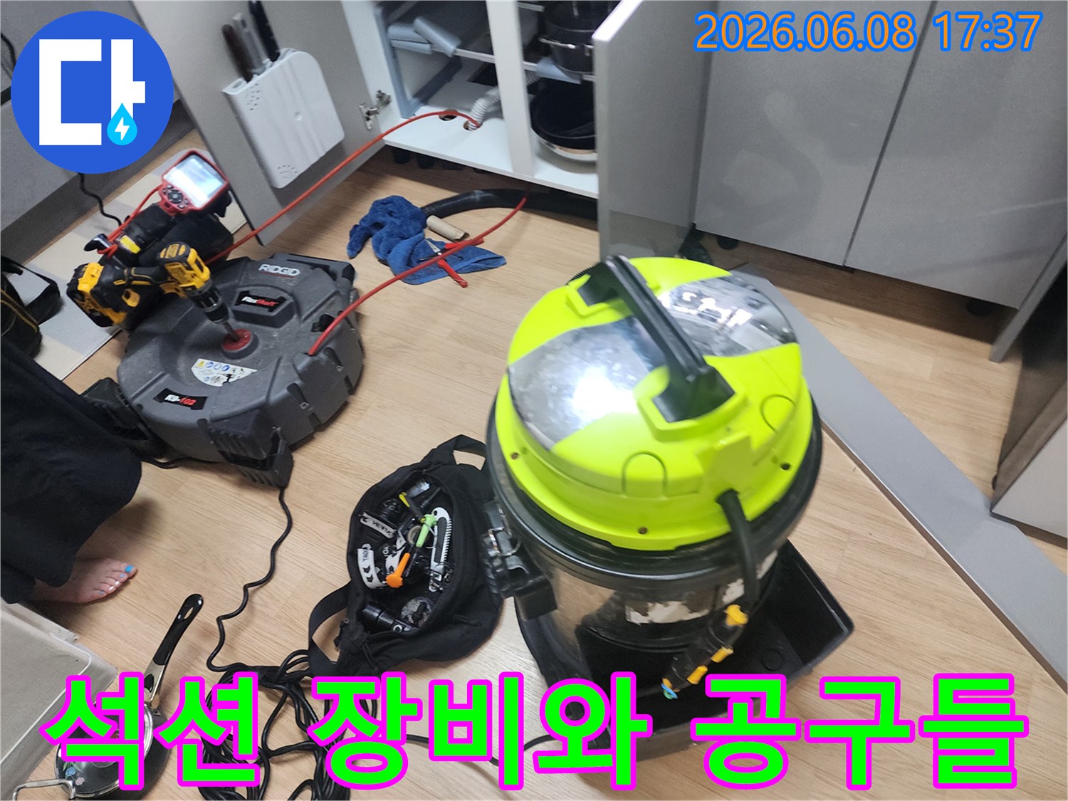 배관 청소를 위해 싱크대 밑에 배치된 석션기와 전동 드릴