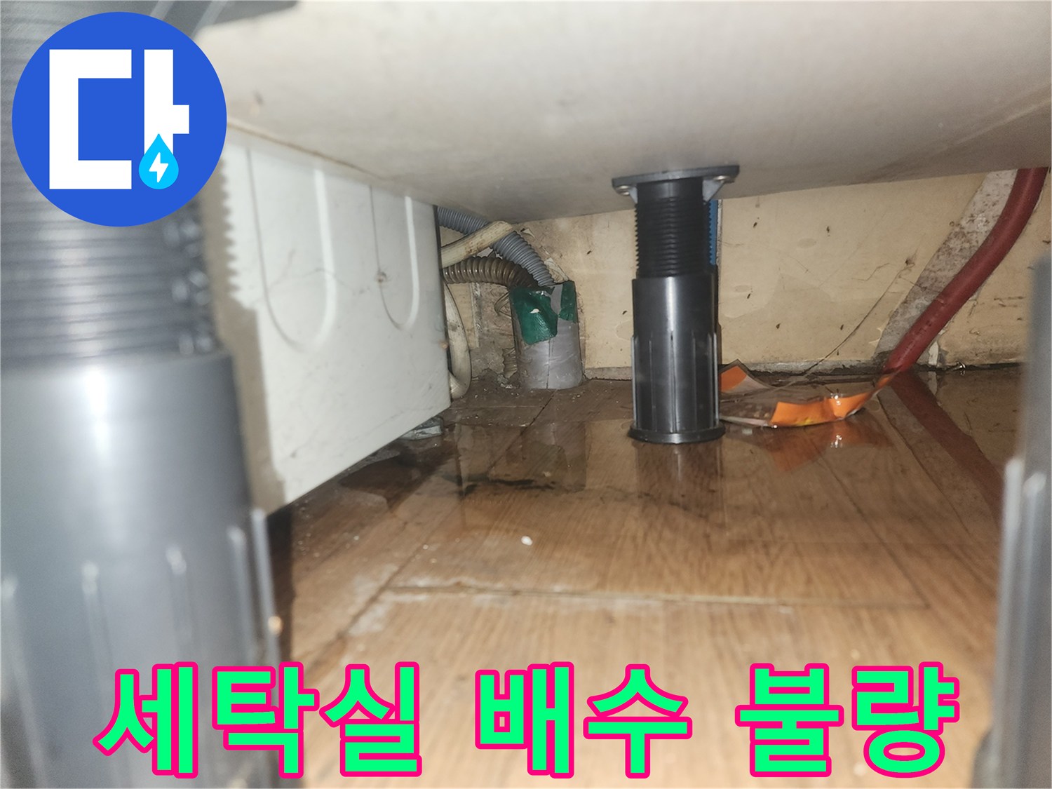 세탁기-아래-바닥에-물이-고여있는-모습으로-배수-불량으로-인한-누수-현장을-보여줍니다