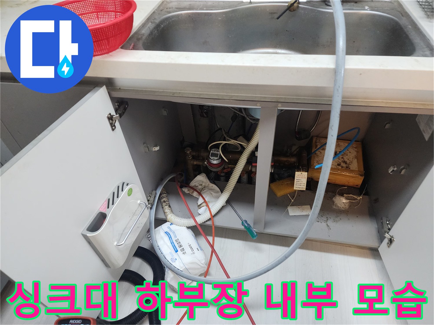 복잡하게 연결된 싱크대 아래 배수 호스와 점검 장비들