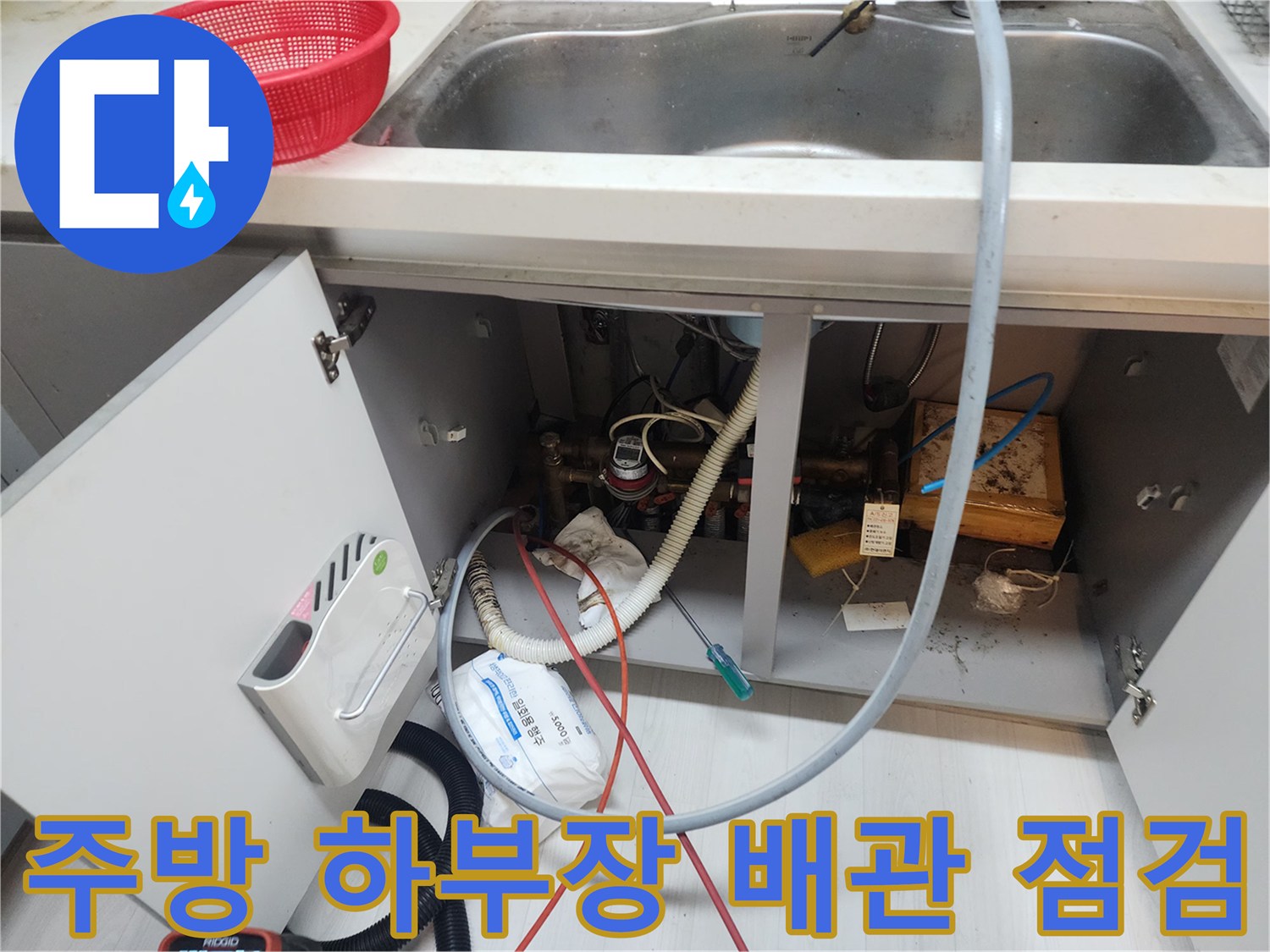 싱크대 아래쪽의 복잡한 배수 호스와 연결된 배관 상태입니다.