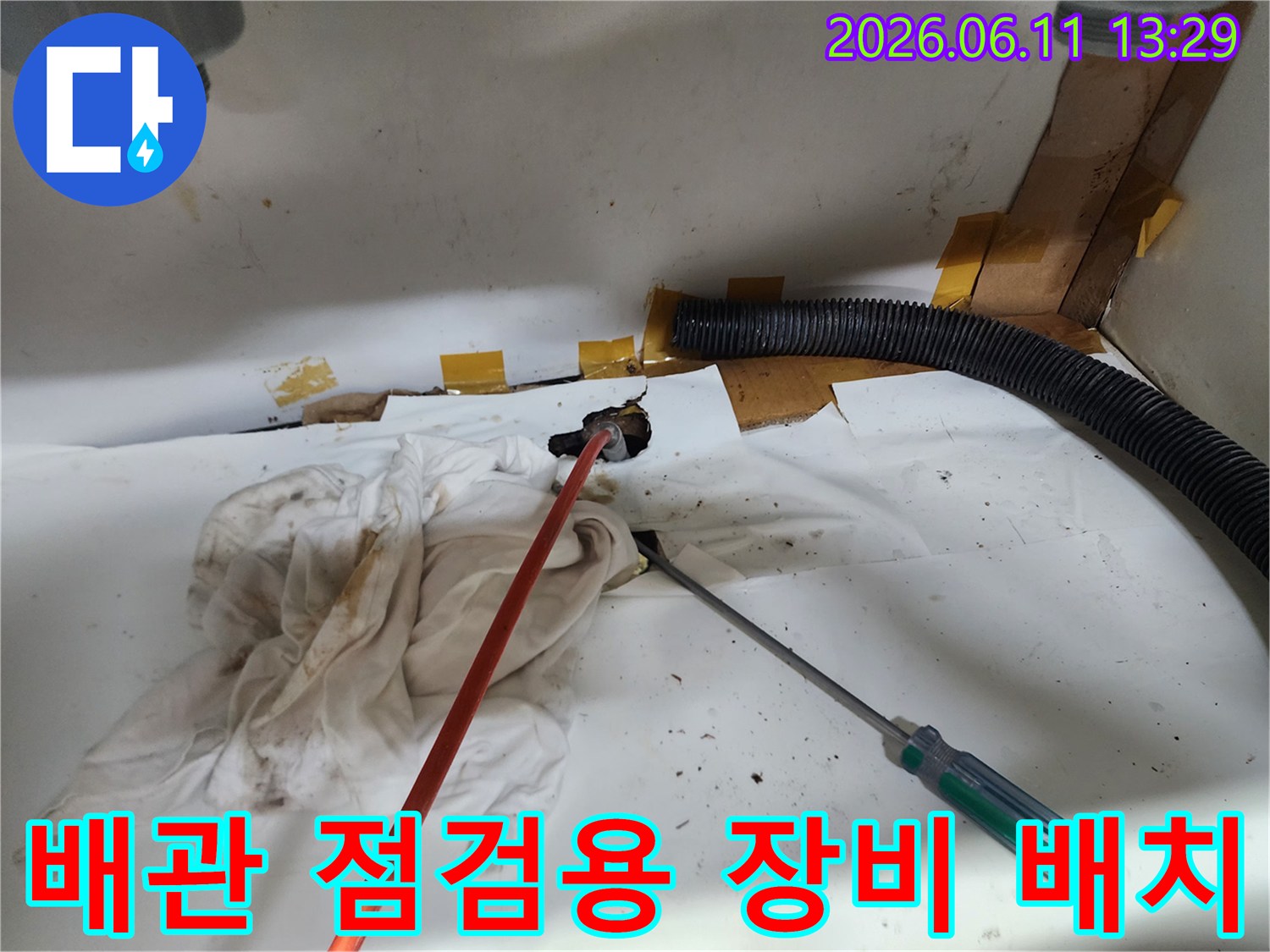 하수구 배관 연결 부위와 작업 도구가 놓인 싱크대 하부장