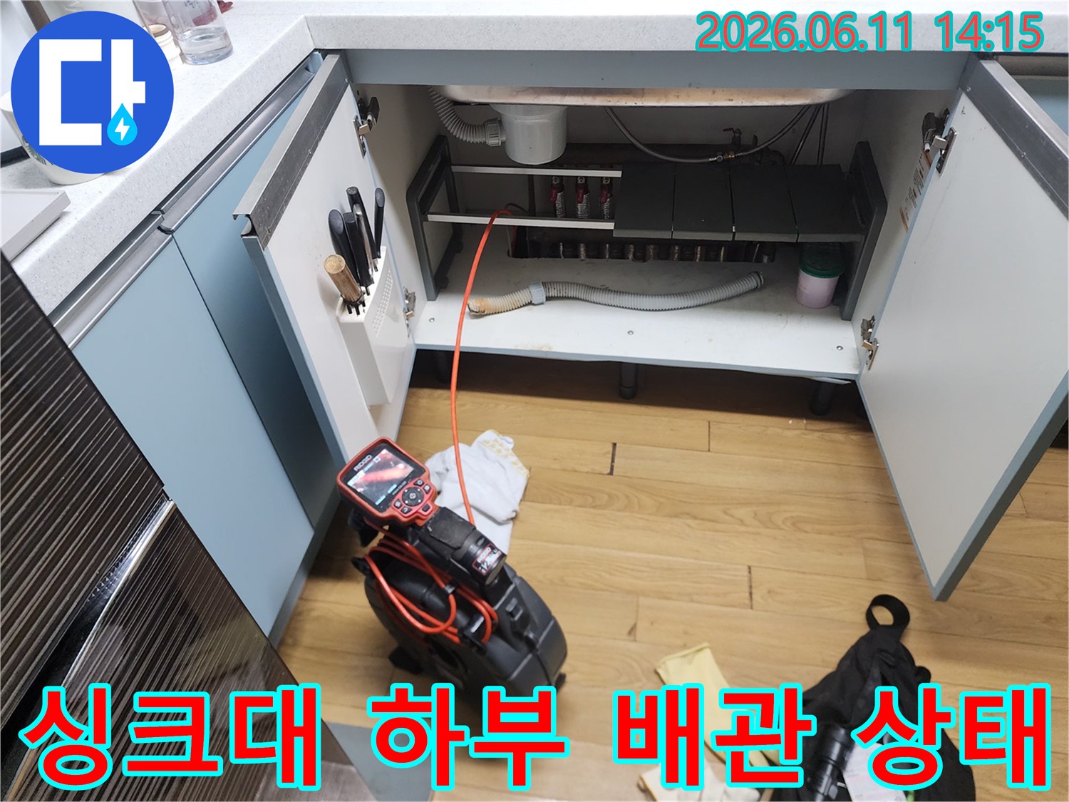 싱크대 하부장 내부 배수 호스와 석션 장비가 놓인 현장 사진