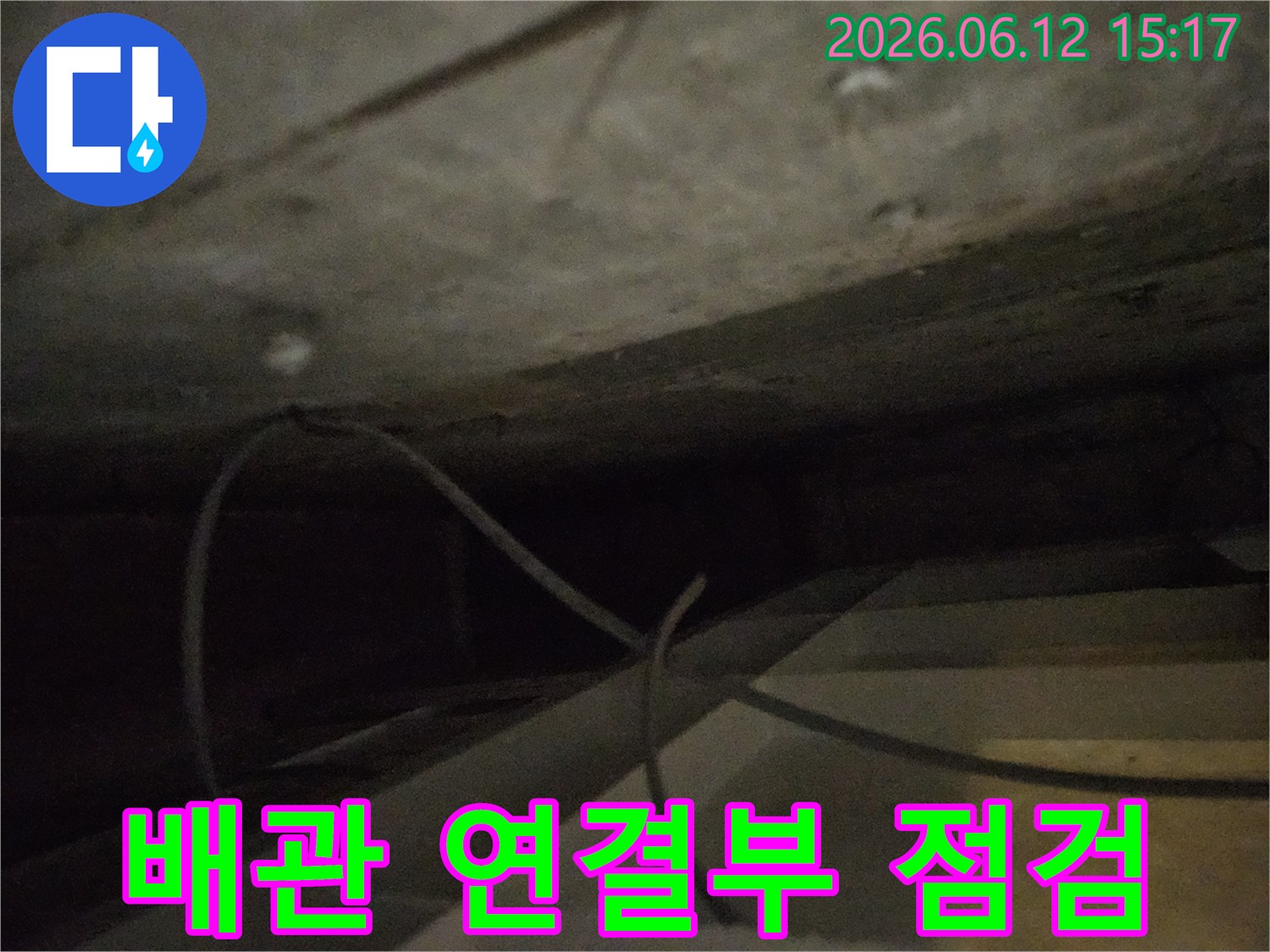 어두운-틈새에서-배관-연결부위의-누수-여부를-집중적으로-점검하는-사진입니다