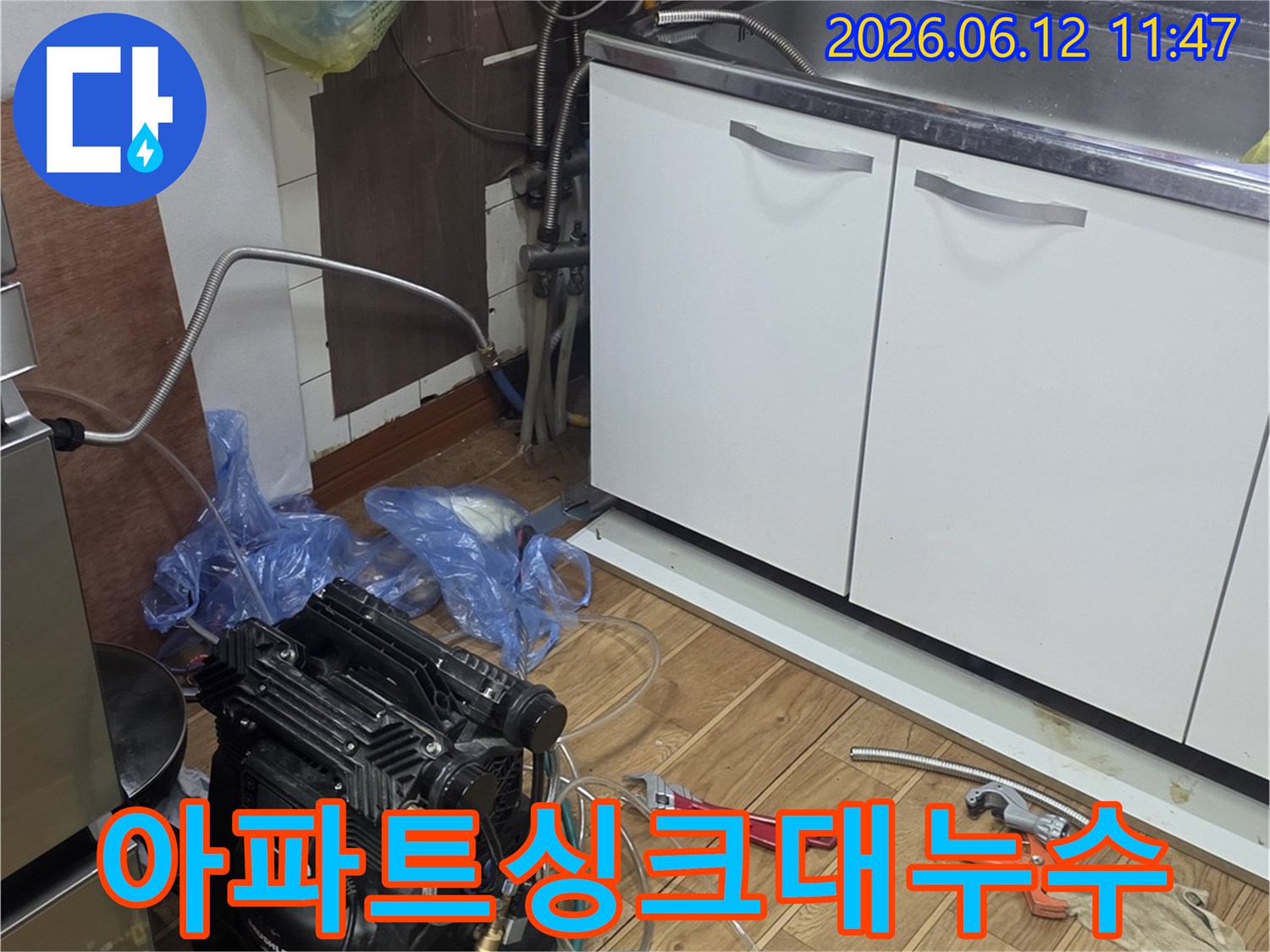 아파트 주방 싱크대 하부에서-누수 탐지 장비를 연결하여-배관 문제를 점검하는 모습