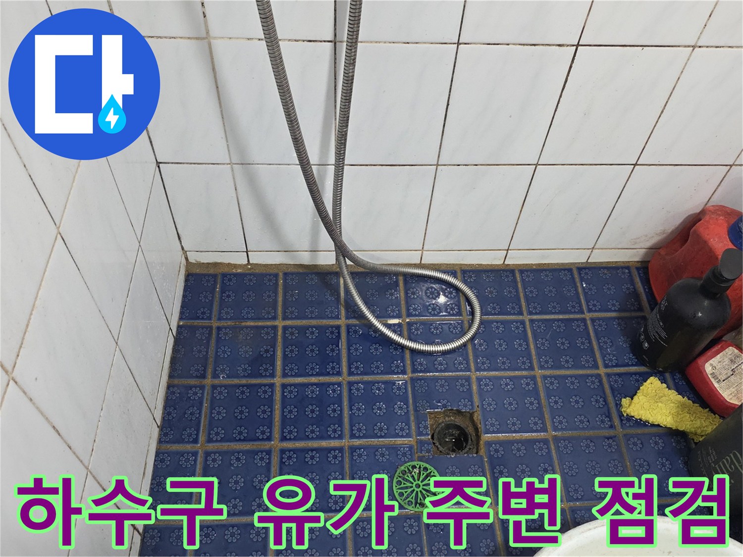 파란색 타일 바닥의 배수구 구멍과 샤워 호스 연결부