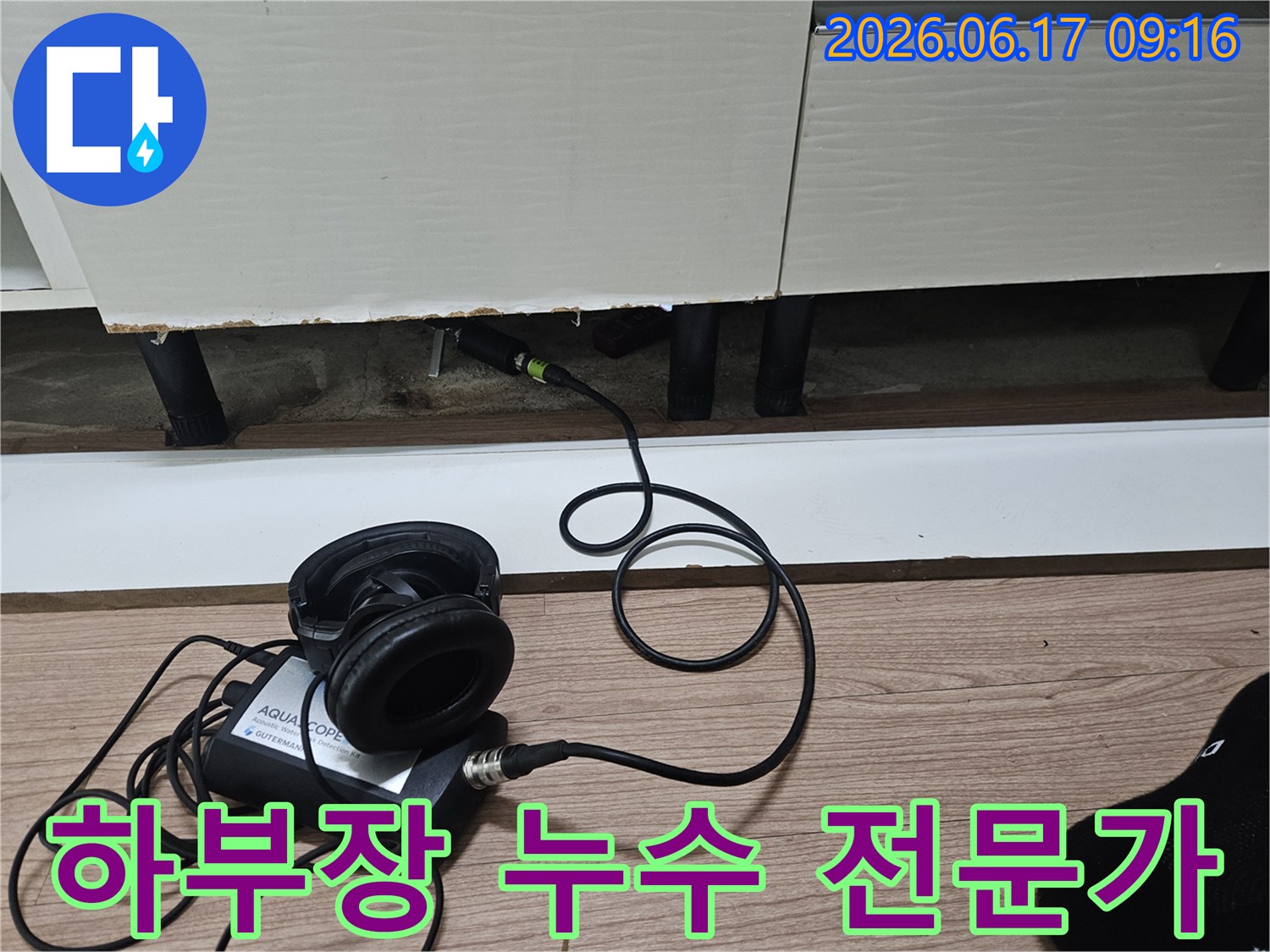 누수 탐지 전문가가-청음식 장비를 사용하여-싱크대 하부장 아래 누수 지점을 탐지하는 모습